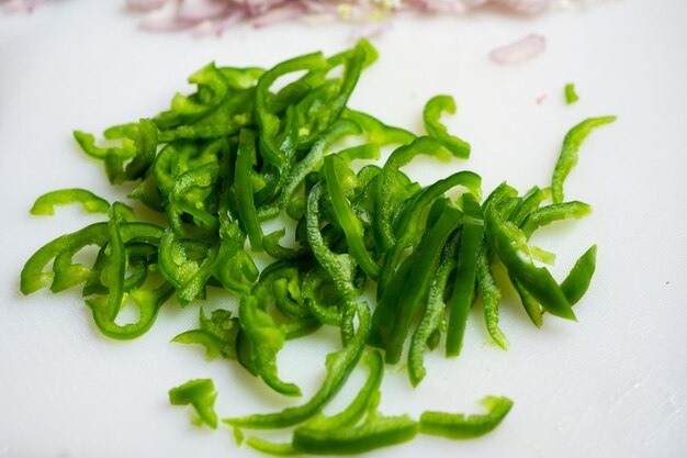 Green bell pepper cut to length on a white cutting board