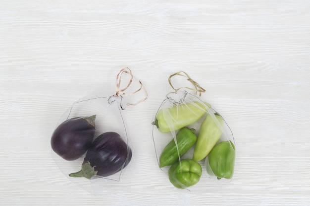 Green bell peppers and eggplants in reusable bags