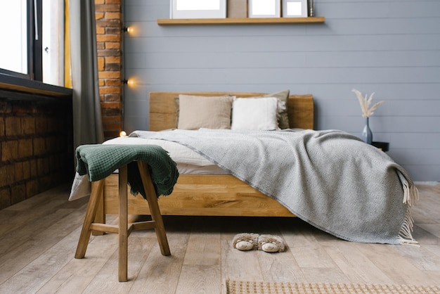 スカンジナビアスタイルの寝室のベッドのそばのスツールの緑の毛布