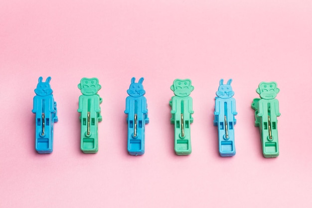 Green and blue plastic clothespins on a pink background