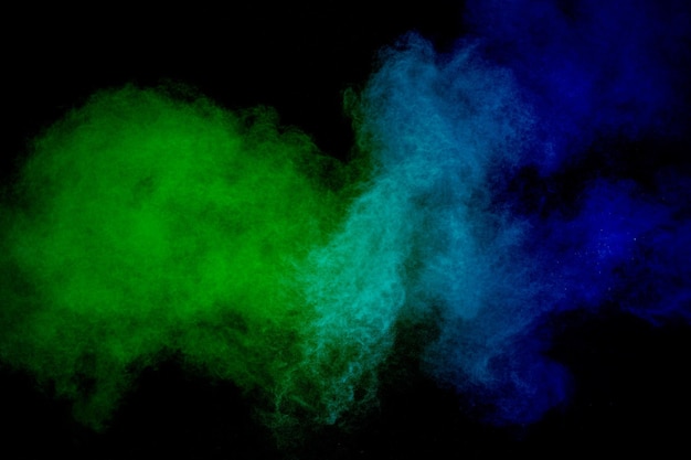 검정색 배경에 녹색 및 파란색 분말 폭발녹색 및 파란색 먼지 구름의 움직임을 정지