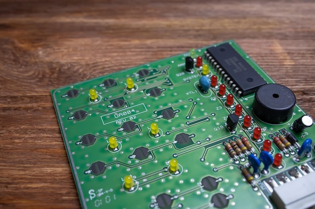 A green board with transistors lies on a wooden table