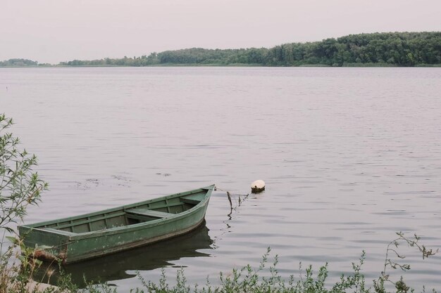 Green boat on the river against the backdrop of the forest