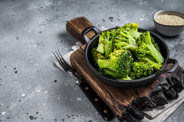 Green boiled broccoli cabbage in pan. Gray background. Top view. Copy space.