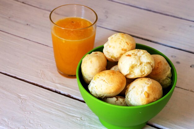 Green bowl with cheese rolls and orange juice