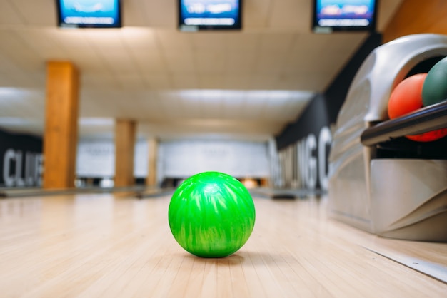 Foto palla da bowling verde sul pavimento di legno nel club, vista del primo piano, nessuno. concetto di gioco della ciotola