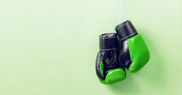 Green boxing gloves on a green wall background Copy space for text