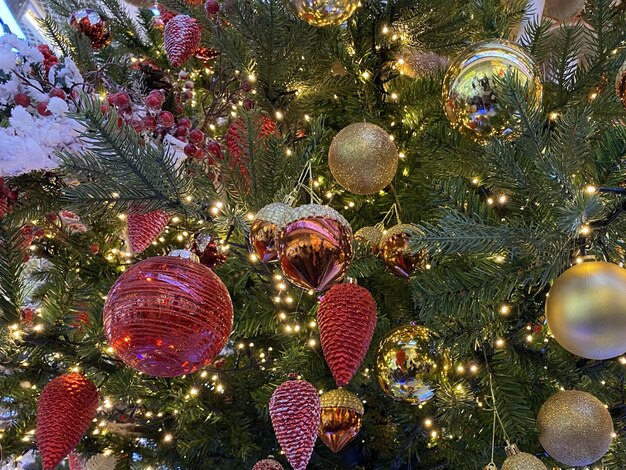 Green branches of a fluffy christmas festive new year tree with toys in balls and bright glowing