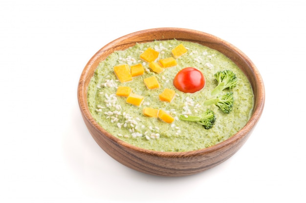 Green broccoli cream soup in wooden bowl isolated. side view.