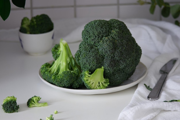 Green broccoli lies on a white plate on the table close up