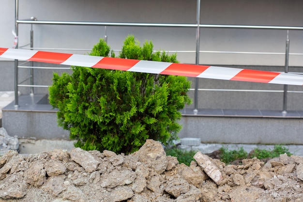 修理作業が行われる場所には、赤い特殊テープで囲われた緑の低木草が生えています。