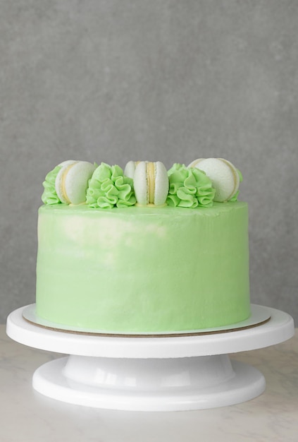 Green cake on a stand with macaroons and cream with copy space