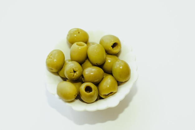 Green canned olives in a white bowl on the table