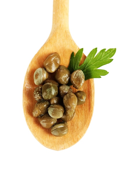 Green capers in wooden spoon on white background closeup