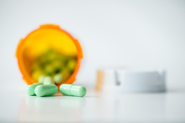 Photo green capsules cascading out of orange bottle