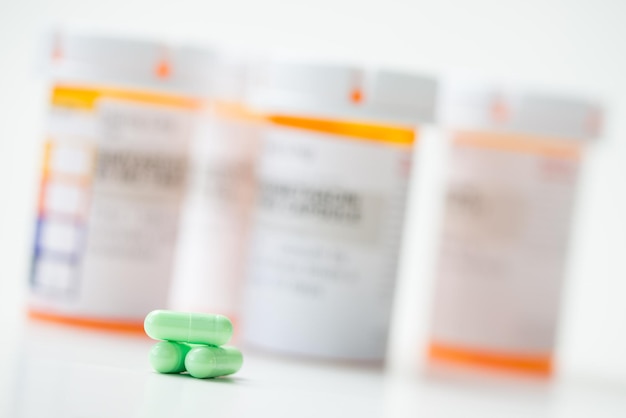 Photo green capsules in front of orange pharmacy bottles