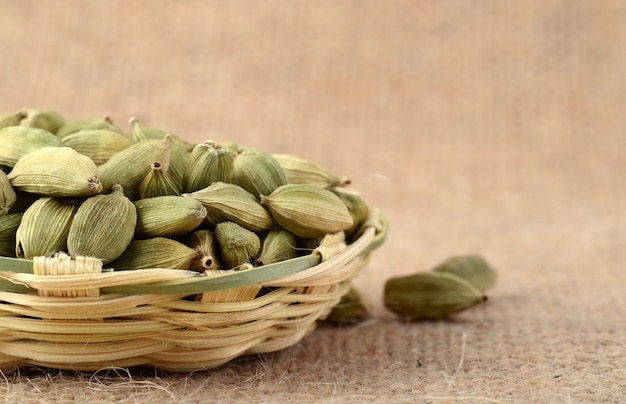 Baccelli di cardamomo verde nel cesto di bambù sul panno del sacco