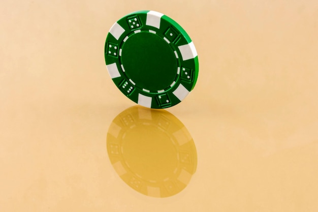 Photo green casino chip is worth an edge on the reflective surface