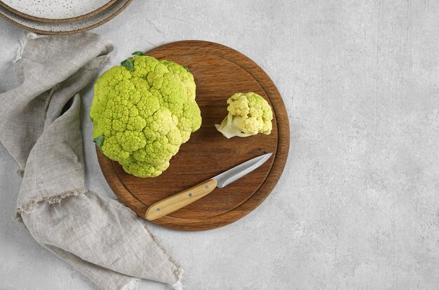 Green Cauliflower on the wooden board with knife and napkin top view copy space