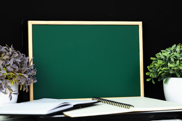 green chalkboard with pile of notebook pape