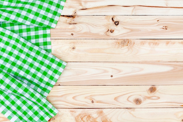 Green checkered tablecloth on wooden table, top view