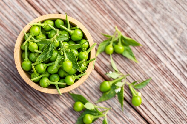 Green cherry peppers in wooden bowl on table