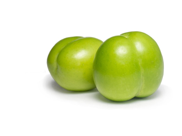 Green cherry plum on a white background Fruit for making tkemali sauce Sweet and sour fruit