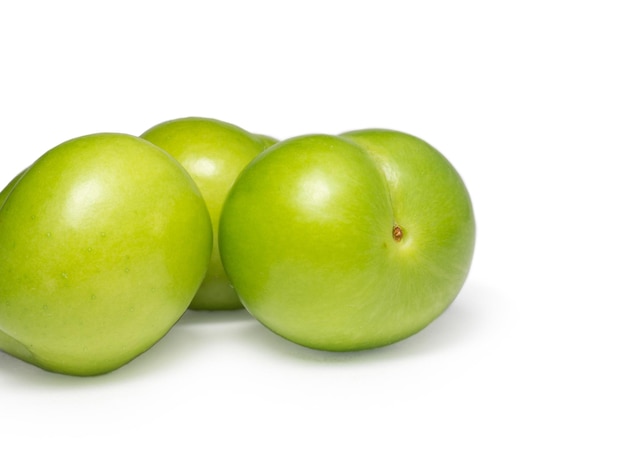 Green cherry plum on a white background Fruit for making tkemali sauce Useful fruit