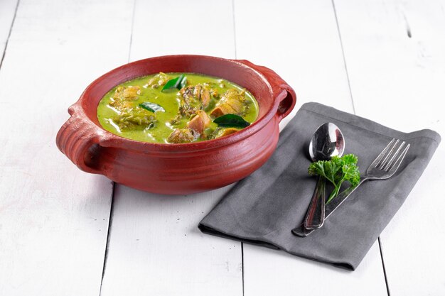 Green Chicken curry with raw ingredients which is arranged in an earthen ware