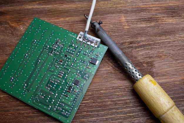 Photo next to the green chip on the wooden table is a soldering iron