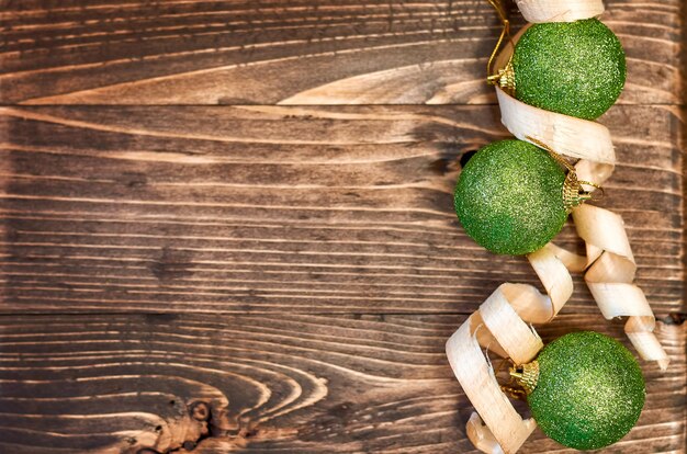 Green Christmas balls and wood shavings on a wooden background