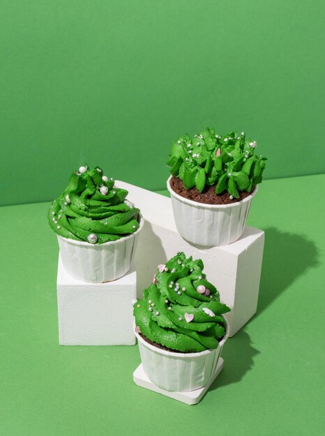 green christmas tree shaped cupcakes on white poduims abstract and modern minimal style
