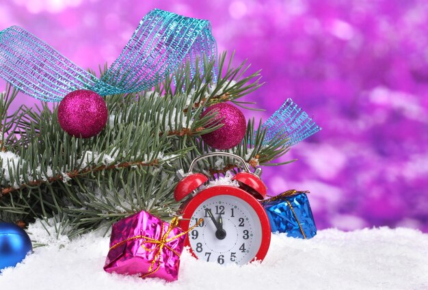 Green Christmas tree with toy and clock in the snow on purple