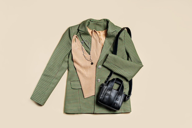 Photo green classic jacket and beige women's top with handbag. women's stylish autumn or spring trendy clothes. fashion concept. flat lay, top view.