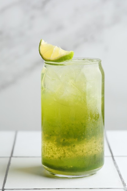 Green cocktail or lemonade with lime on light background closeup. Green Gin cocktail on bar table