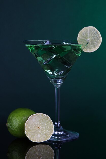 Green cocktail with lime on dark green background