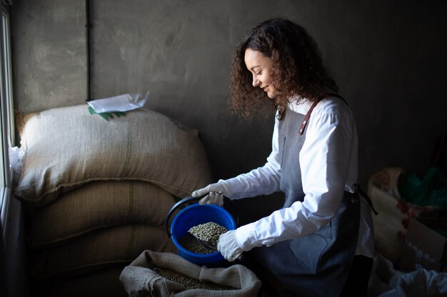 Green coffee beans in burlap sack and woman worker roaster with scoop