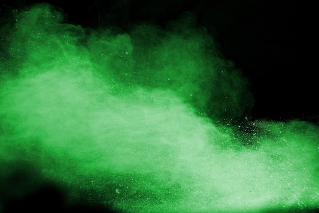 Green color powder explosion cloud isolated on black background.