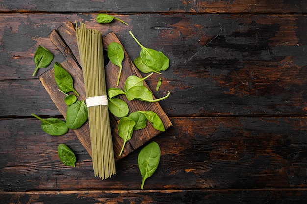 Green colored spaghetti raw dry spinach set, on old dark  wooden table background, top view flat lay, with copy space for text