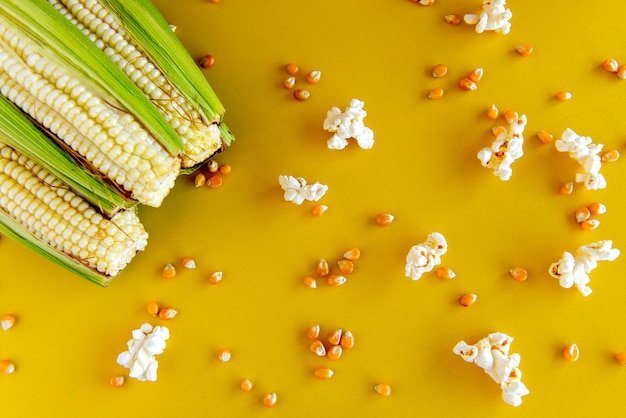 Photo green corn and popcorn on a yellow background