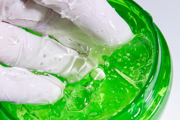 green cosmetic or medical gel is scooped up by a gloved hand