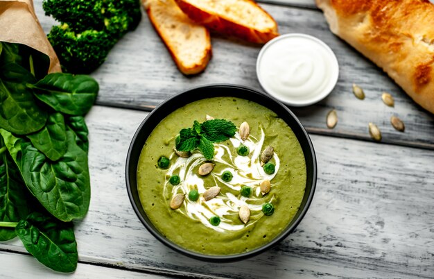 ほうれん草とブロッコリーのグリーンクリームスープ。木材の背景に健康的な食事と食事の概念。