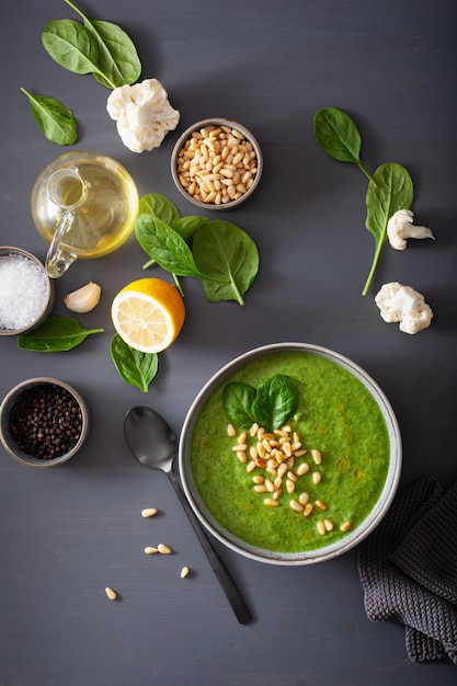 Green creamy cauliflower spinach soup on gray background