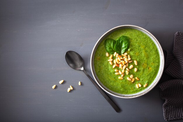 Green creamy cauliflower spinach soup on gray