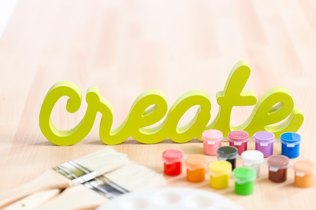 Green create sign with paint brushes on the table.