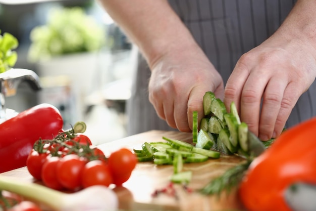 Green cucumbers are cut with knife in kitchen