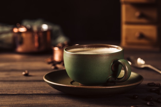 Green cup of coffee with coffee grinder