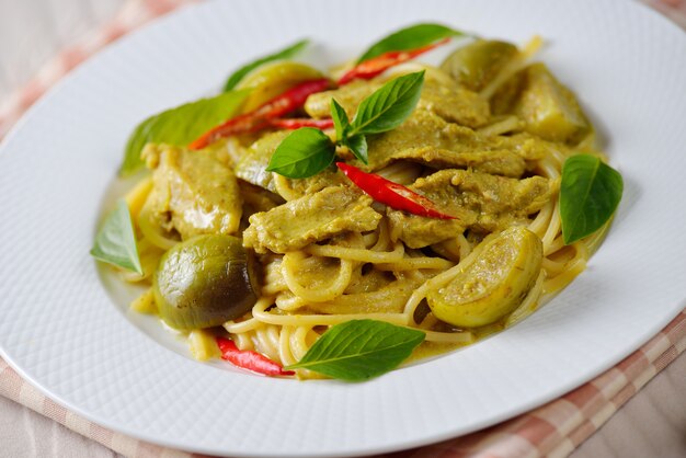 Spaghetti al curry verde su un piatto bianco