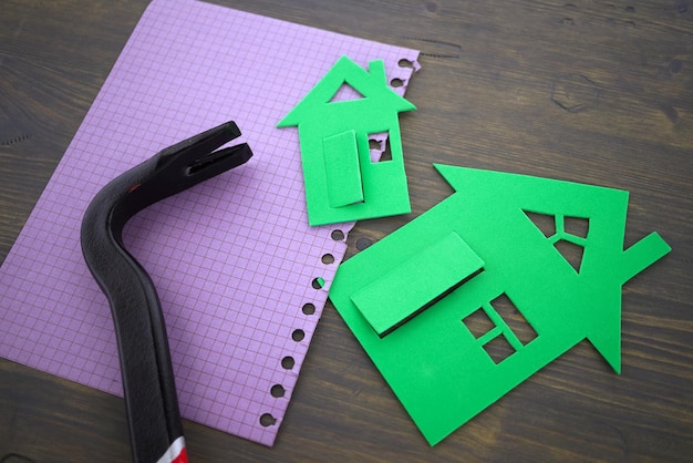 Green cutouts of model houses with hand tool on a memo notepad