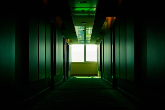 Green dark empty corridor in a hotel in perspective floor in a\
hotel a window in the hallway the light at the end of the\
tunnel